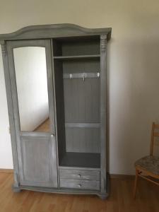 un mobiletto di legno con uno specchio in una stanza di Gemütliche Ferienwohnung für 6 Personen im Schloss Kastorf a Knorrendorf Altre 2 foto