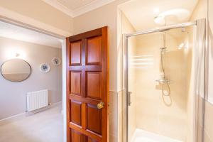 a bathroom with a shower and a wooden door at Corrie House with Hot Tub in Belladrum