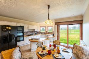 a kitchen with a wooden table and chairs and a kitchen with a counter at Corrie House with Hot Tub in Belladrum