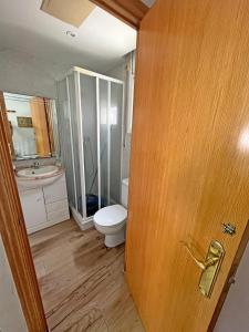 a bathroom with a toilet and a wooden door at CASA EN VILAFORTUNY CON BARBACOA PISCINA COMUNITARIa in Cambrils +8 photos