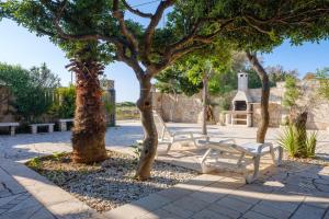 two white benches sitting under trees in a park at Villa Assunta in Lecce