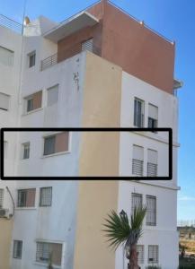 a tall white building with a palm tree in front of it at Appartement tanger Beach in Tangier