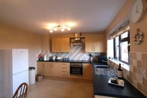 a kitchen with wooden cabinets and a white refrigerator at Lovely two bed home in Cemaes, Anglesey in Cemaes Bay
