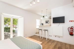 a white bedroom with a bed and a kitchen at Setúbal CityCenter Studios in Setúbal