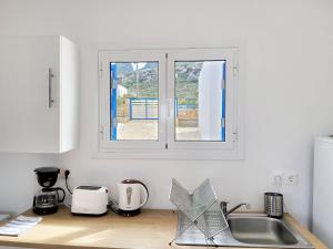a kitchen counter with a sink and a window at SempreViva Sea Houses in Diakofti