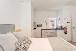 a white bedroom with a bed and a kitchen at Setúbal CityCenter Studios in Setúbal