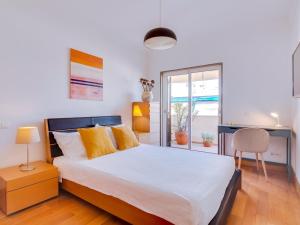 een slaapkamer met een bed, een bureau en een raam bij AL - Quarteira Terrace Penthouse in Quarteira