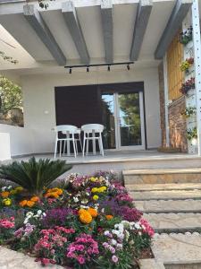 a porch with two white stools and a flower garden at Sea Gem Apartment in Dhërmi