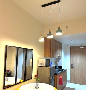 a kitchen with a table and a refrigerator and lights at Casa Abigail Shore 3 in Manila