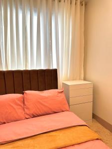 a bedroom with a bed and a window with white curtains at Casa Abigail Shore 3 in Manila