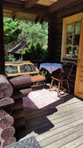 una veranda di una baita di tronchi con una sedia e una porta di Gojaus smukle a Molėtai