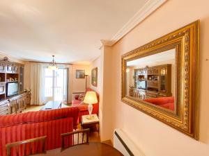sala de estar con sofá rojo y espejo enmarcado en oro en Apartamento Los Leones, en Berlanga de Duero
