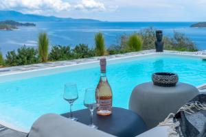 a bottle of wine and two glasses next to a swimming pool at Indigo Boutique Home in Skiathos Town
