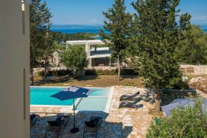 a pool with chairs and umbrellas next to a house at A Casa D' Irene Gaios Paxos in Gaios