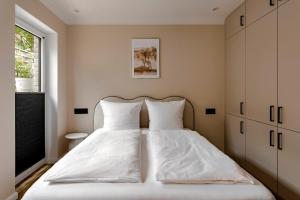 a bedroom with a bed with white sheets and a window at Altstadt Apartments in Friedrichstadt
