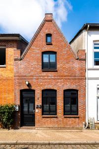 a red brick house with black windows on a street at Altstadt Apartments in Friedrichstadt