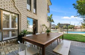 a patio with a wooden table and white chairs at Mooloolaba Waterfront Unit - sleeps 8 in Mooloolaba