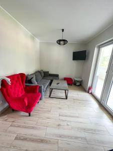 a living room with a couch and a red chair at Apartamenty 53 in Wielen Zaobrzanski