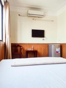 查羅的住宿－Hùng Đức Hotel Cửa Lò，卧室配有一张床,墙上配有电视。