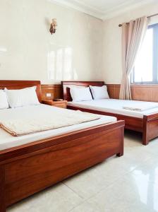 2 camas en una habitación con ventana en Hùng Đức Hotel Cửa Lò, en Cửa Lô