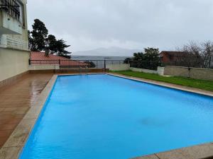a large blue swimming pool next to a building at Precioso apartamento con piscina in Pontevedra