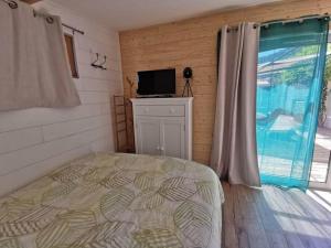 a bedroom with a bed and a television and a window at chalet proche de la mer in La Crau