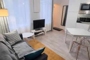 a living room with a couch and a tv and a table at Apollinaire - Très jolie maison - Jardin - 3pers in Lille