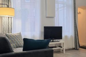 uma sala de estar com um sofá e uma televisão em Apollinaire - Très jolie maison - Jardin - 3pers em Lille