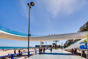 a bridge over a beach with people on the beach at HB Apartments - Luceros Luxury Loft in Alicante