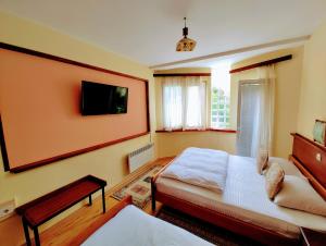 a bedroom with a bed and a tv on the wall at Hotel Kapistec Skopje in Skopje