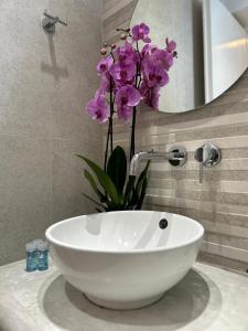 baño con lavabo blanco con flores púrpuras en Sea View Apartments & Studios, en Agia Anna de Naxos