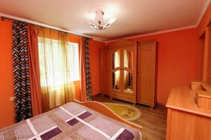 a bedroom with orange walls and a bed and a window at Cottage "Kliverent" in Yaremche