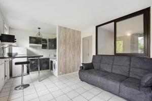 ein Wohnzimmer mit einem Sofa und einer Küche in der Unterkunft Le Glatigny- Chesnay in Le Chesnay