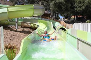 uma mulher e uma criança num escorrega aquático num parque aquático em Camping Le Petit Rocher em Longeville-sur-Mer