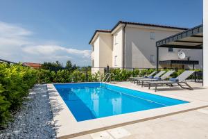 una piscina con due sedie a sdraio accanto a una casa di Villa Bella a Klimno
