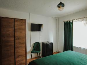 a bedroom with a green bed and a green chair at Casa Laptici - statiunea Pestera-Padina, Bucegi in Moroeni
