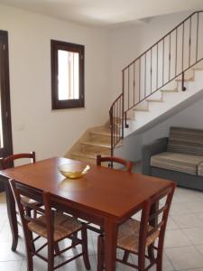 ein Esszimmer mit einem Tisch, Stühlen und einer Treppe in der Unterkunft Vacanze Morfino in Castelluzzo