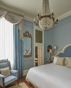 um quarto com uma cama, um candelabro e uma cadeira em Henrys Townhouse Marylebone em Londres