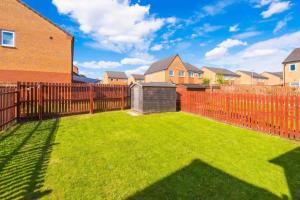 a backyard with a fence and a yard with green grass at Spacious 5 Bedroom Home Hosted By MCR Dens in Manchester