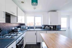 a kitchen with white cabinets and a wooden counter top at Spacious 5 Bedroom Home Hosted By MCR Dens in Manchester