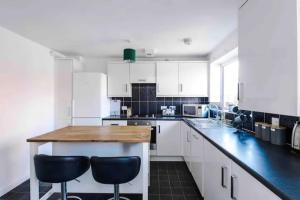 eine Küche mit weißen Schränken und einer hölzernen Arbeitsplatte in der Unterkunft Spacious 5 Bedroom Home Hosted By MCR Dens in Manchester