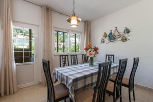 a dining room with a table with chairs and a vase of flowers at VIlla Ribar in Podgora