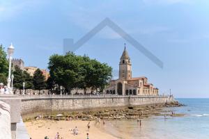 a group of people on a beach next to the ocean at Apartamento La Muralla - Gijón in Gijón