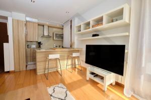 a living room with a large television and a kitchen at Apartamento La Muralla - Gijón in Gijón