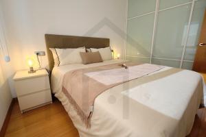 a bedroom with a large white bed and a night stand at Apartamento La Muralla - Gijón in Gijón