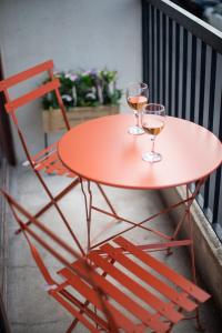 dos copas de vino en una mesa roja en un balcón en Cham's House - T2 Chamalières, en Chamalières