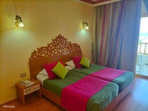 sypialnia z dużym łóżkiem z kolorowymi poduszkami w obiekcie Hôtel LES MIMOSAS TABARKA w mieście Tabarka