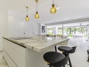 a kitchen with white cabinets and a large island with black chairs at Las Terrazas de Santa Clara in Marbella