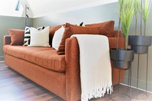 a brown couch with pillows and a white blanket at 17 The Fairways in Broadstairs