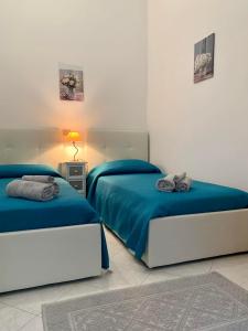 een slaapkamer met twee bedden met blauwe lakens en een lamp bij I Limoni del Sud Sardegna in Assemini